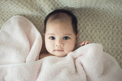 Portrait of cute baby girl lying on bed