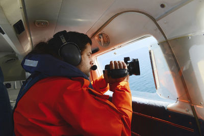 Side view of man shooting video in airplane