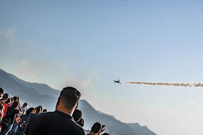 People flying over mountains against sky