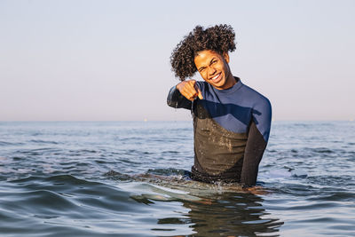 Young woman smiling in sea against sky