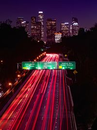 Light trails on street amidst buildings in city at night