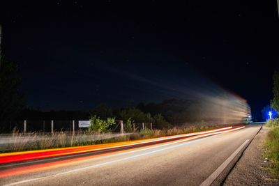 Light trails on road against sky at night