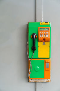 Close-up of pay phone on gray wall