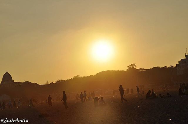 sunset, sun, large group of people, silhouette, water, mountain, building exterior, clear sky, scenics, sea, sunlight, architecture, built structure, tourist, mixed age range, sky, leisure activity, medium group of people, copy space