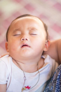 Close-up portrait of cute baby sleeping on bed