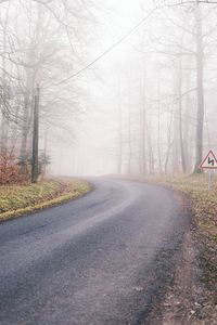 Bare trees on landscape against sky