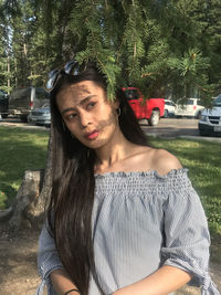 Portrait of beautiful woman standing against trees