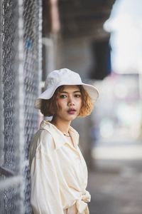 Portrait of beautiful young woman wearing hat standing outdoors