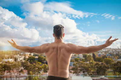 Rear view of shirtless man standing against sky