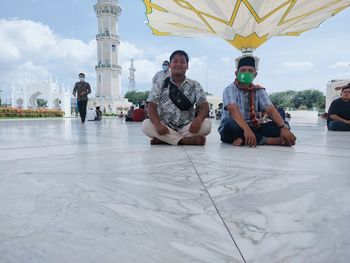 People relaxing on floor against sky