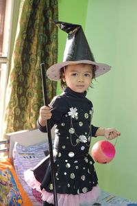 Portrait of smiling girl standing against wall during halloween