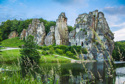 Rock formation by lake against sky