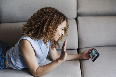 Midsection of woman using mobile phone while sitting on sofa