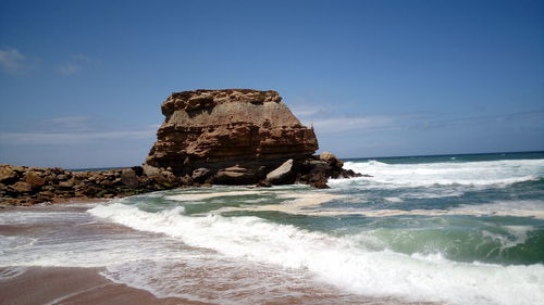 Rocks at beach against sky