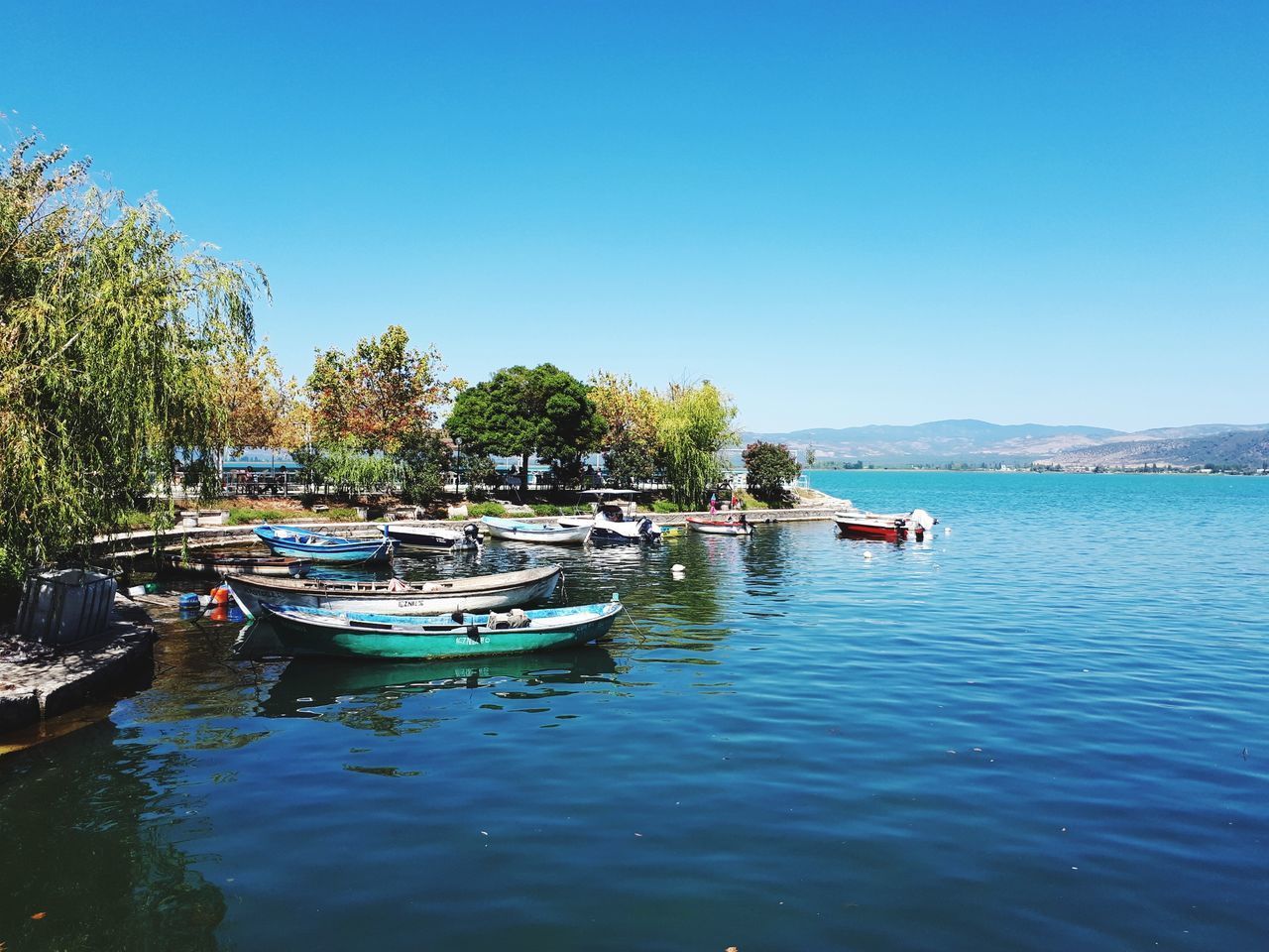 BOATS MOORED ON LAKE AGAINST CLEAR SKY