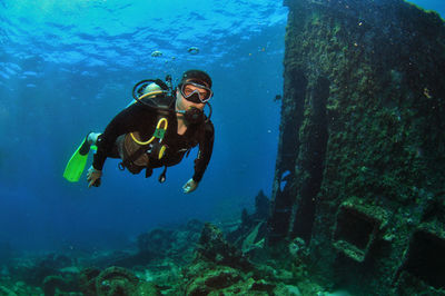 A man doing scuba diving near a shipwreck