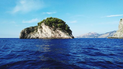 Scenic view of rock formations in calm blue sea against the sky