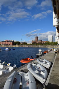 Boats in river by city against sky