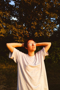 Smiling young woman standing by tree