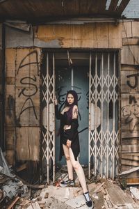 Full length portrait of woman standing against building