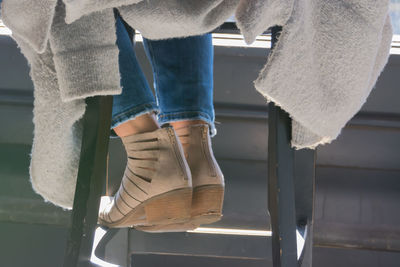 Low section of woman sitting on stool during sunny day