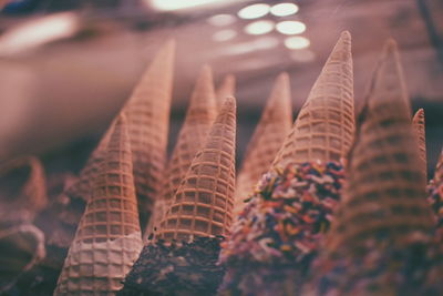 Close-up of ice cream cones seen through glass in parlor