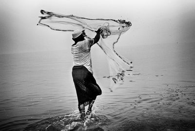 Rear view of woman with umbrella standing on beach