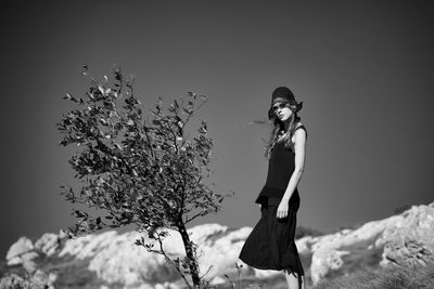 Portrait of young woman standing against sky