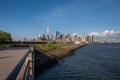 View of buildings by river against blue sky