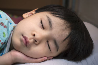 Close-up of young boy sleeping on bed