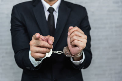 Midsection of businessman with hands trapped with handcuffs