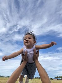 Happy boy with arms raised against sky