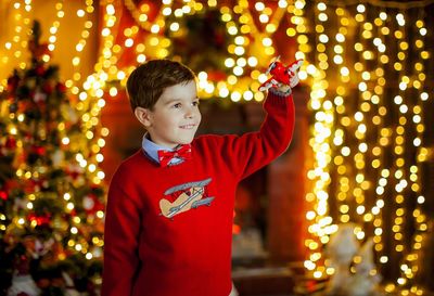 Cute boy playing with toy against illuminated lights