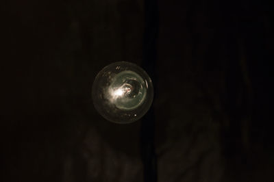 Low angle view of illuminated lamp against black background