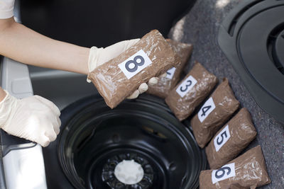 Cropped hand holding cocaine parcels in car