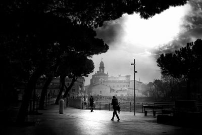 Silhouette people walking on street amidst buildings in city