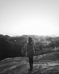 Rear view of woman standing on mountain against clear sky