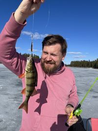 A bearded man has caught a fish on a sunny day.