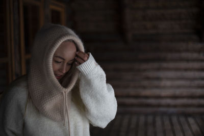 Portrait of young woman standing against wall