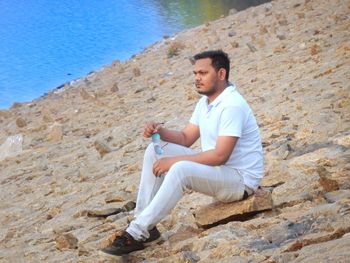 Side view of man sitting on beach