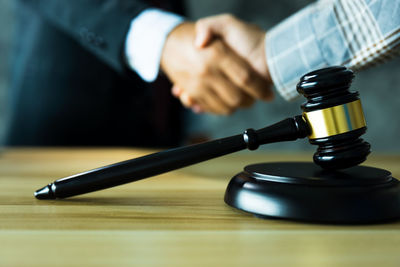 Midsection of lawyer holding gavel on table