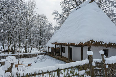 Snow covered houses and trees against sky