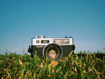 Camera on field against clear blue sky