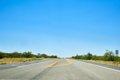 Empty road against clear blue sky