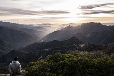 Rear view of man standing on mountain against sky