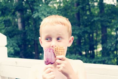 Boy having ice cream against trees