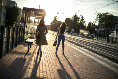 People on railroad tracks against sky