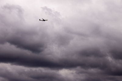 Low angle view of airplane flying against cloudy sky