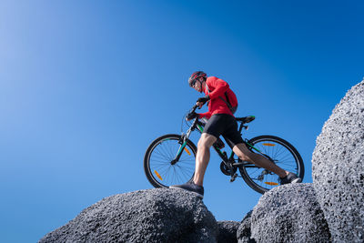 Low angle view of man riding bicycle on rock