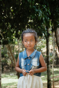 Portrait of cute girl standing on tree